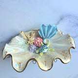 Decorative shell-shaped dish with colorful seashell decorations on a marble surface